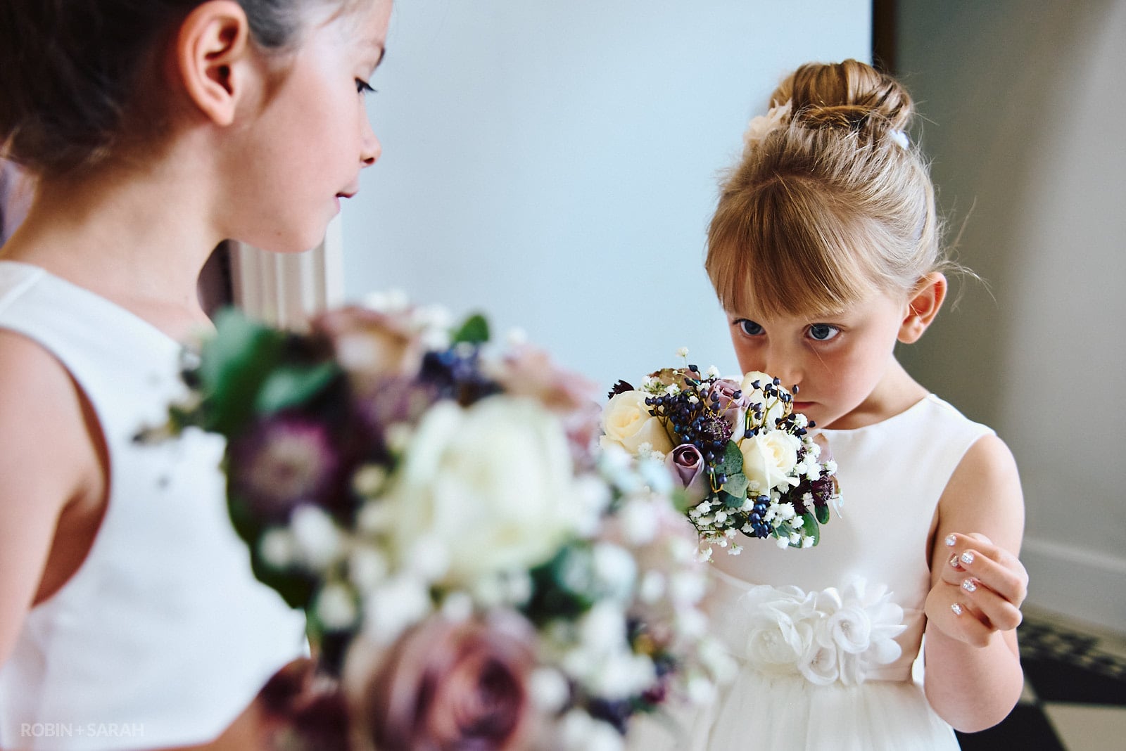 Flowergirl smells wedding flowers at Stanbrook Abbey