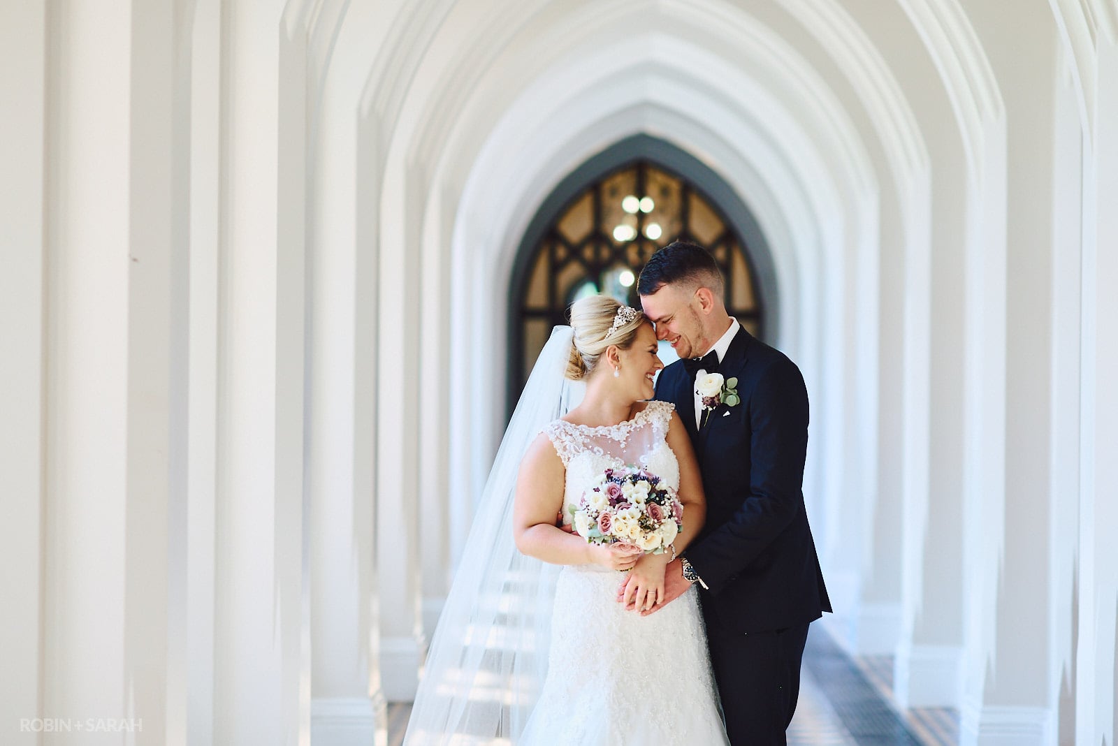 Bride and groom in arched cloisters at Stanbrook Abbey