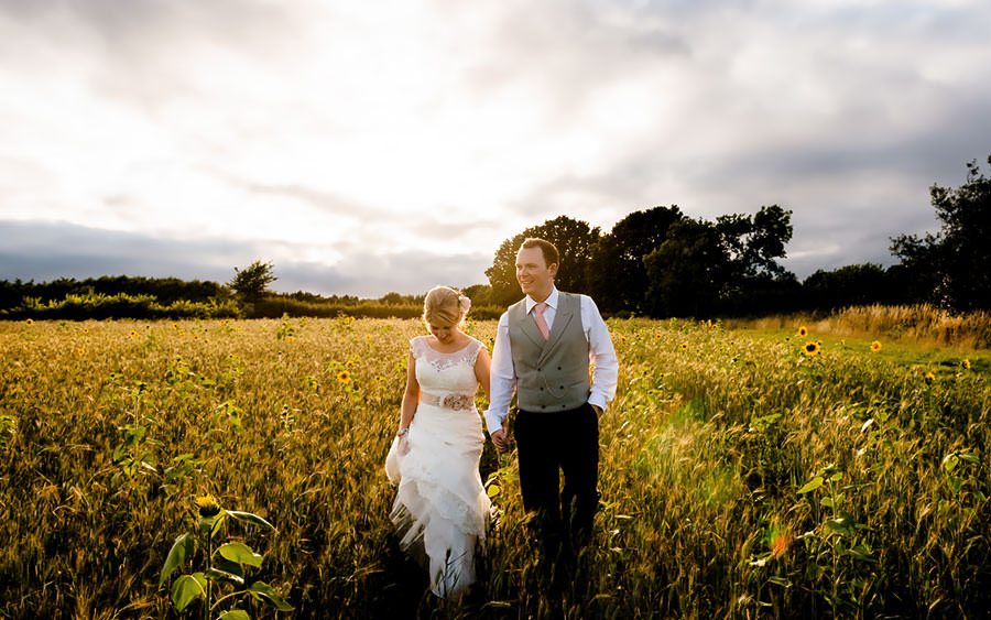 Bride and groom walk through field at Wethele Manor