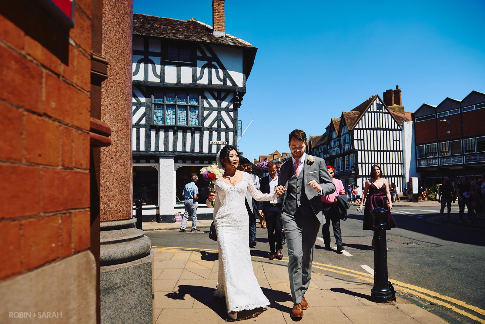 Bride, groom and wedding guests walk through Stratford upon Avon town centre