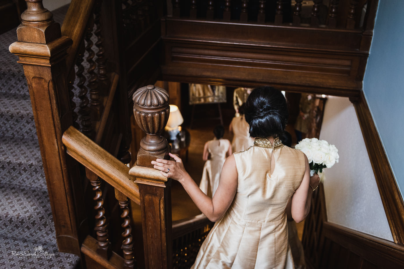 Bridesmaids on staircase at Pendrell Hall in traditional Indian outfits