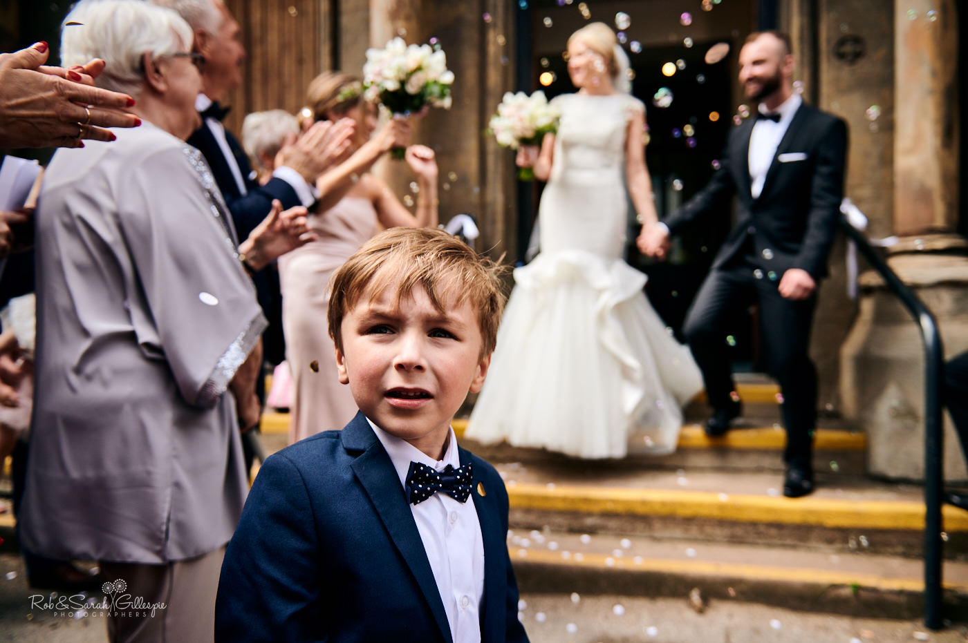 Young boy looks back as bride and groom have confetti thrown