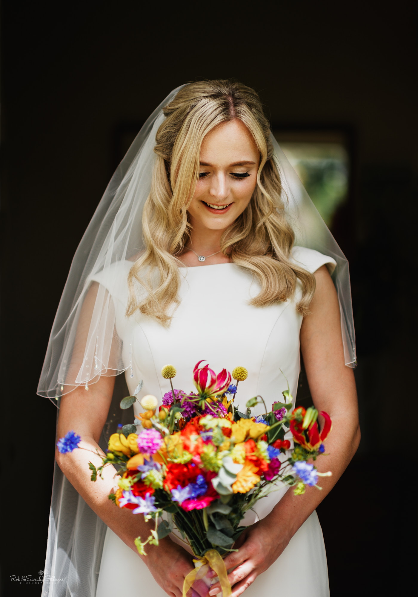 Portrait of bride in beautiful light holding colourful bouquet of flowers