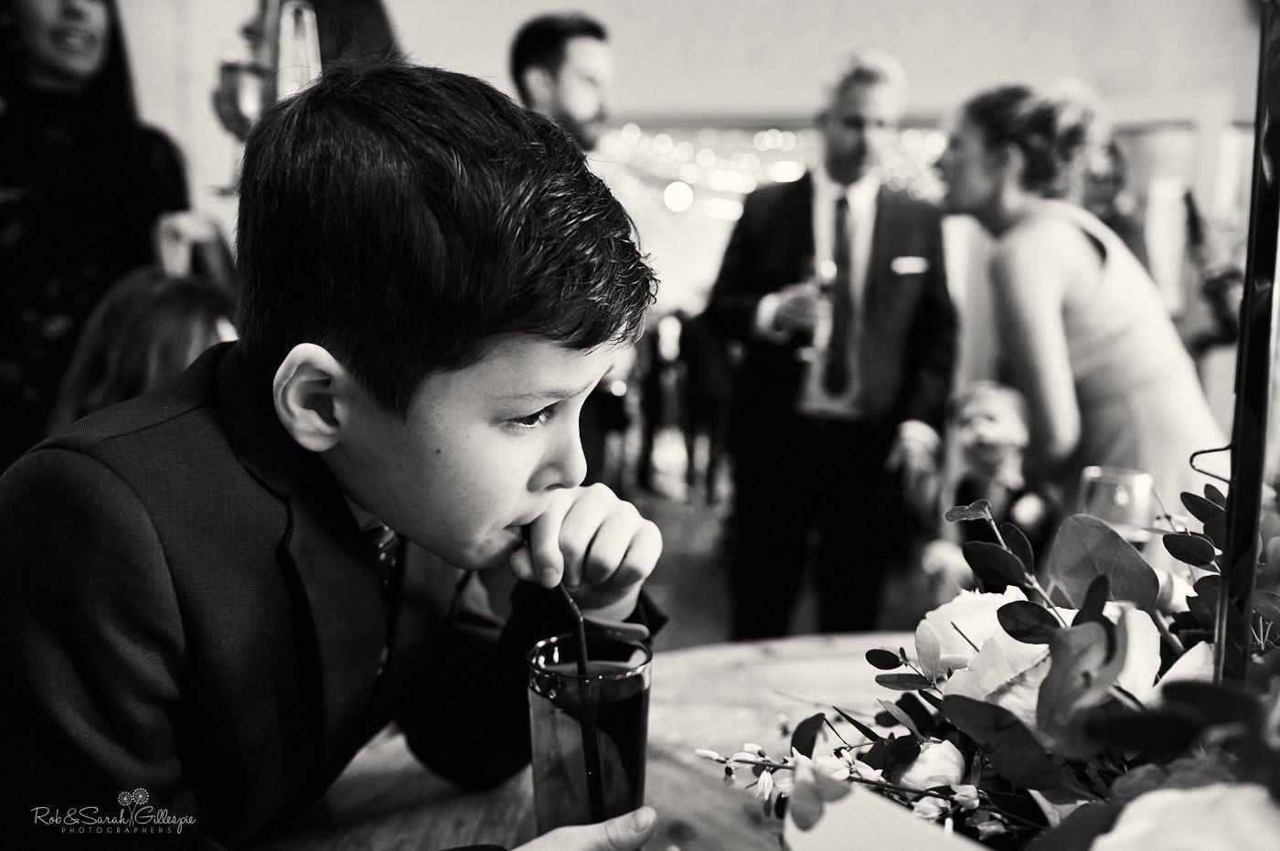 Young boy drinks through straw at wedding reception