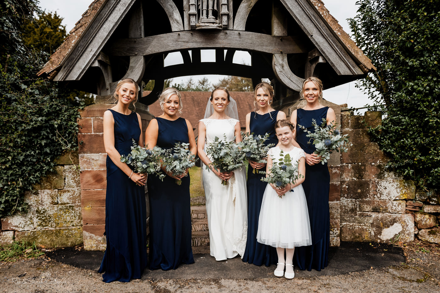 Bride and bridesmaids group photo at St Kenelm's church in Romsley, Worcestershire