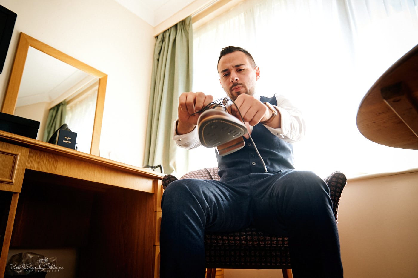 Groom puts on shoes while getting ready for wedding