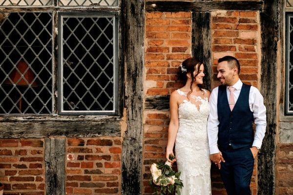Bride & Groom leaning against old brick wall at Gorcott Hall