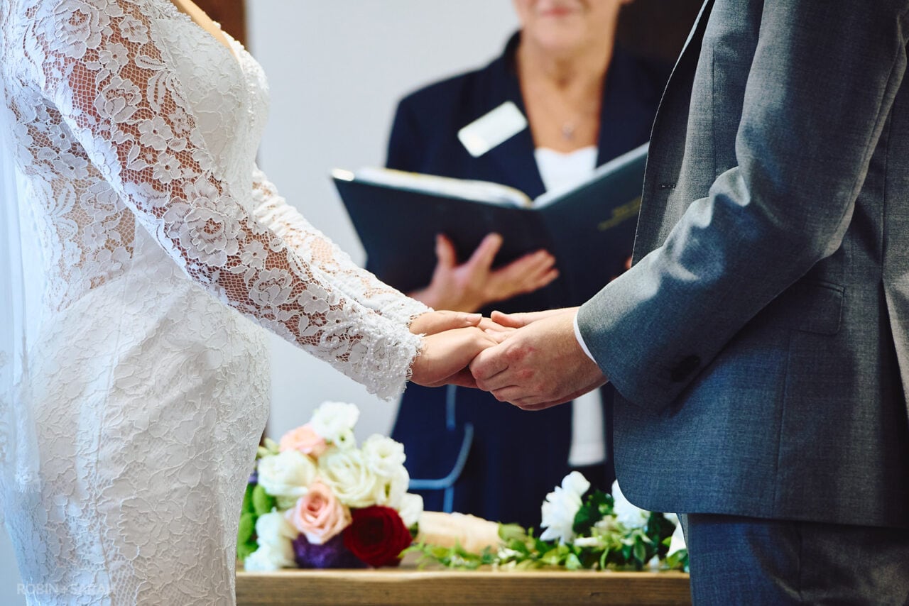 Bride and groom hold hands during wedding ceremony