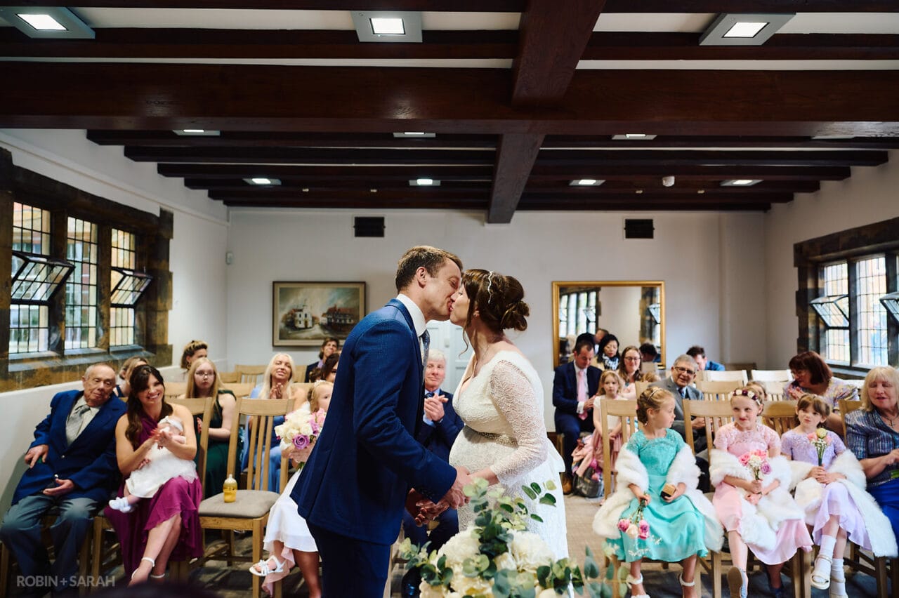 Bride and groom kiss during wedding at The Henley Room