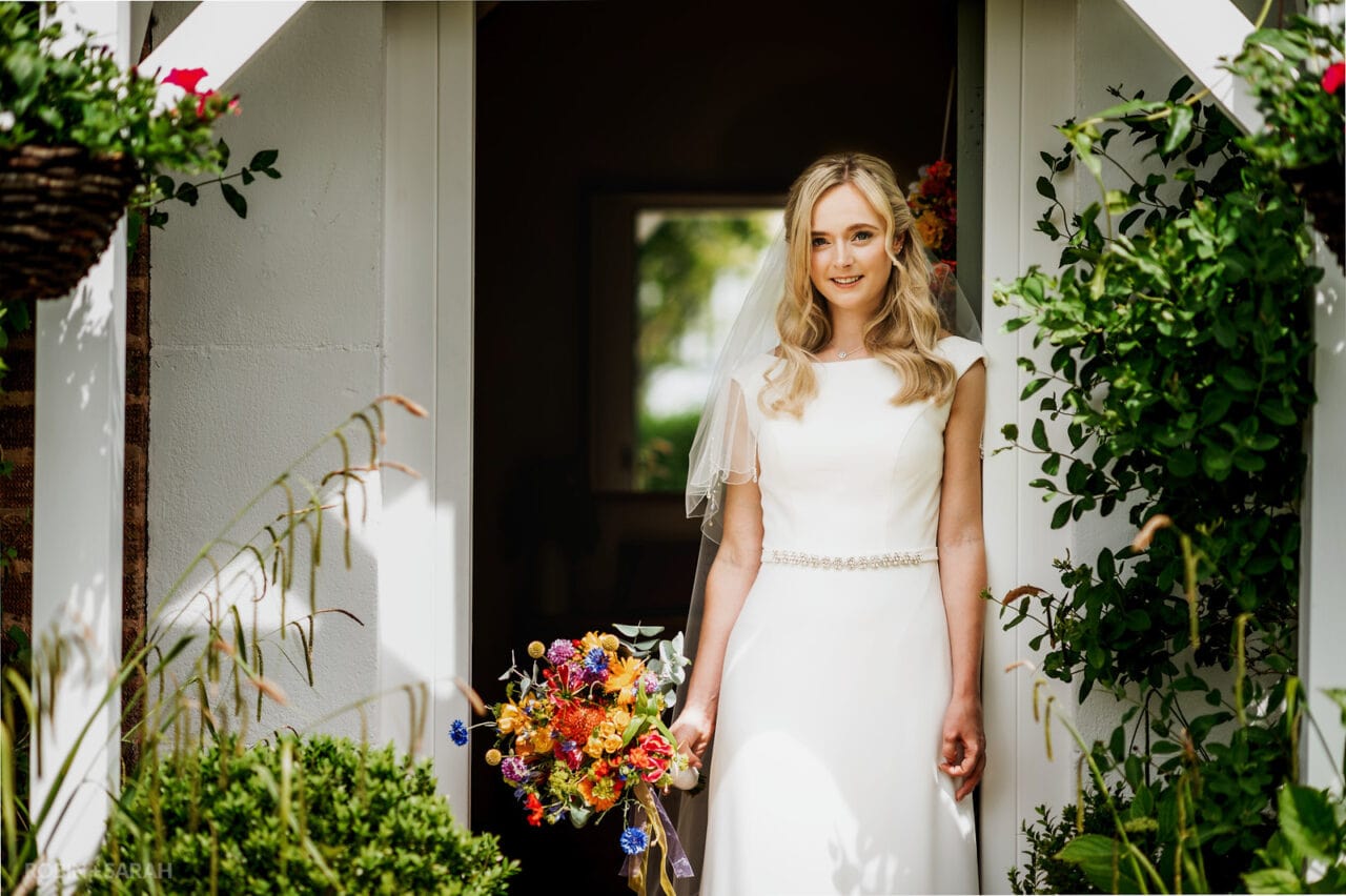 Portrait of bride in doorway surrounded by gardens