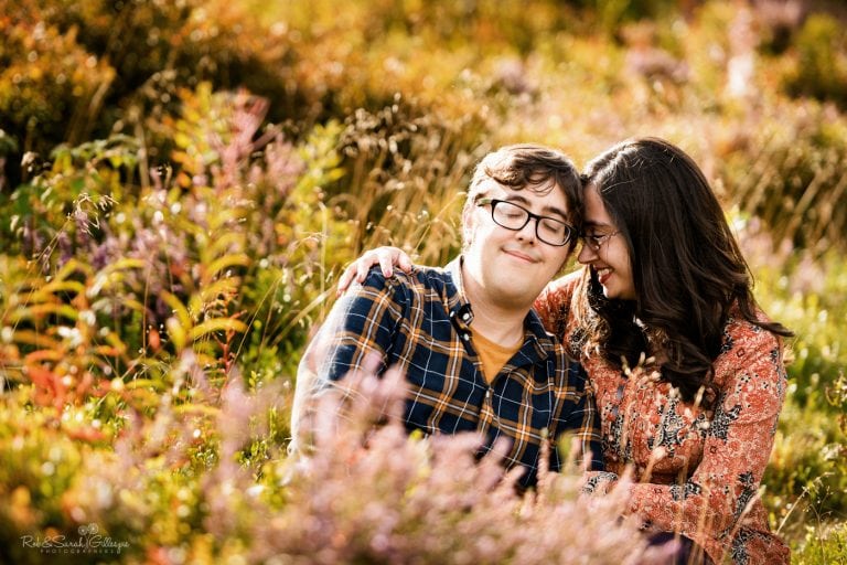 Engagement photo shoot couple sitting in heather and laughing