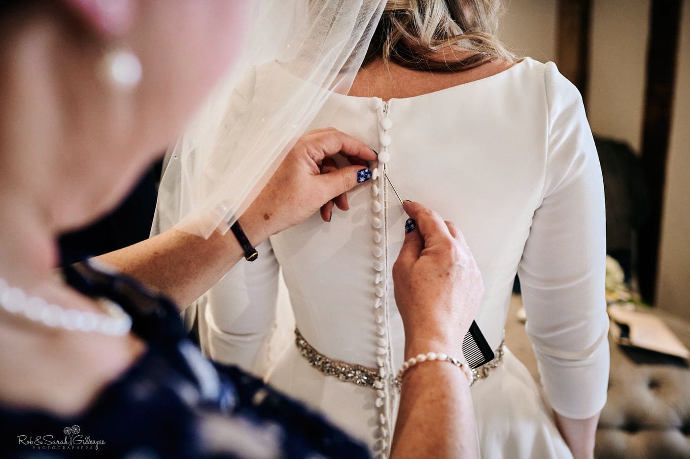 Bride's mum fastens daughter's wedding dress