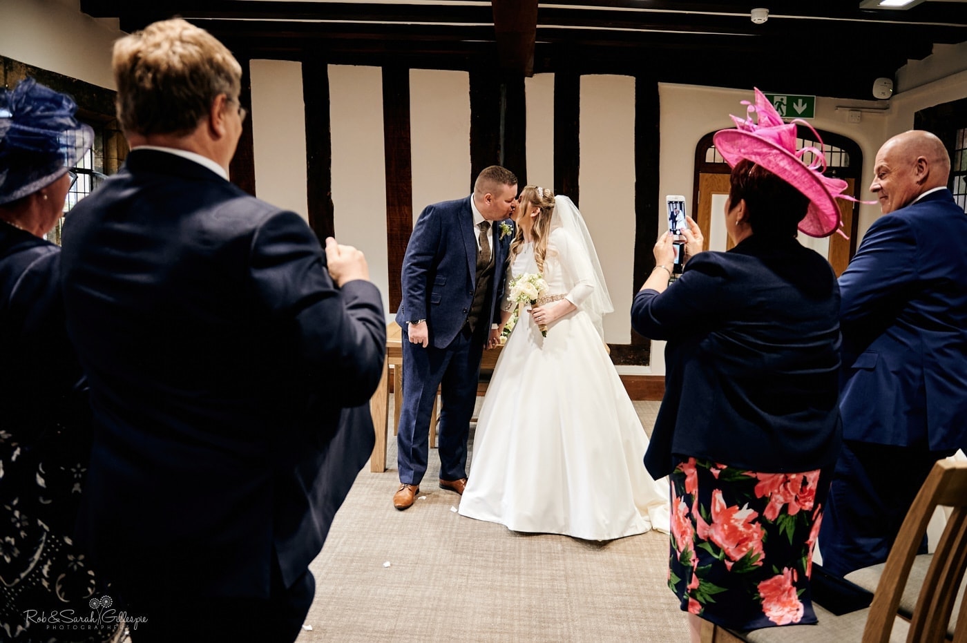 Bride and groom kiss before leaving wedding ceremony in The Henley Room