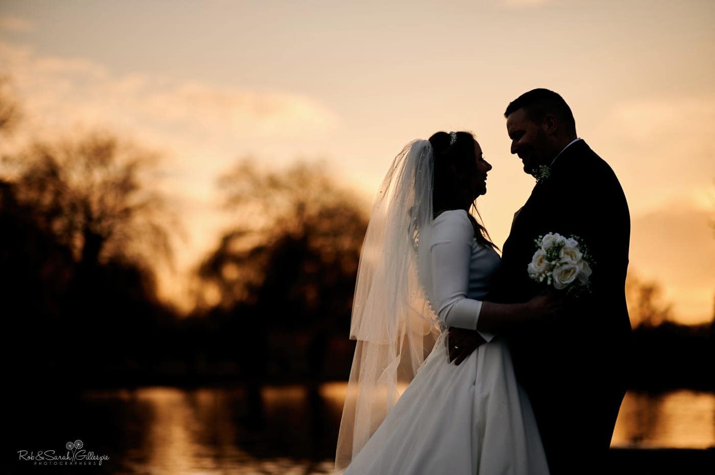 Bride and groom silhouetted against susnet in Stratford upon Avon