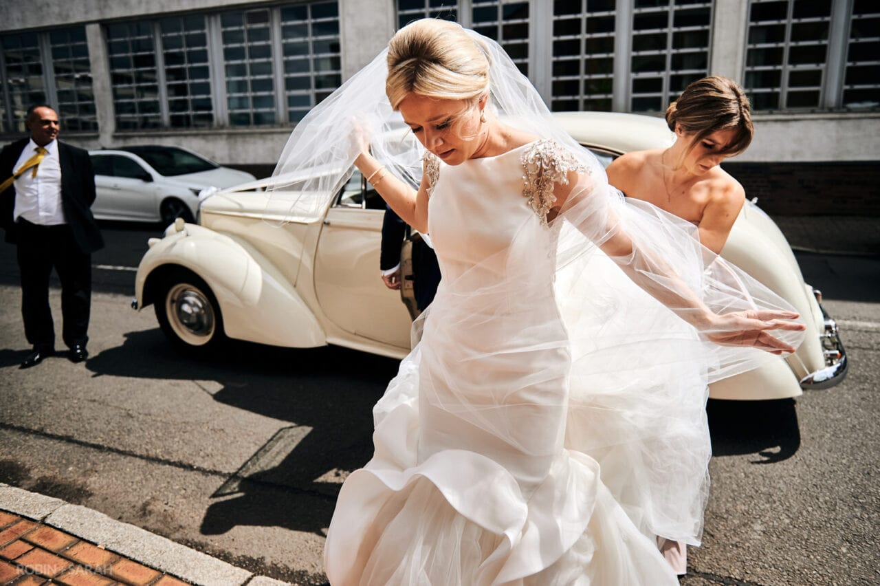 Bride struggles with veil as she gets out of wedding car