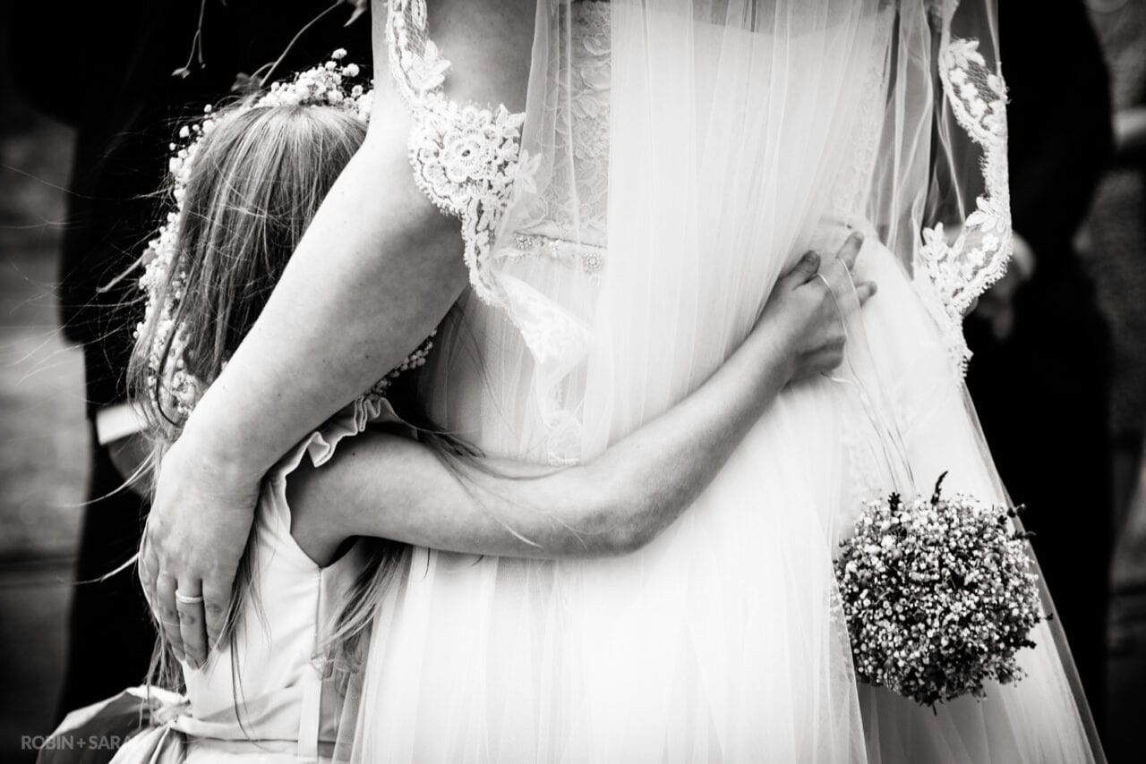 Flowergirl hugs bride