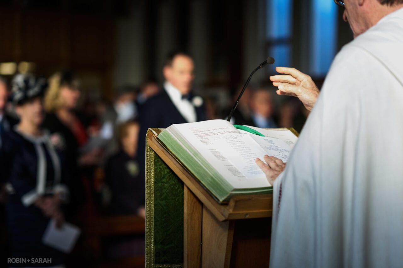 Vicar's hands as he reads from bible during wedding ceremony