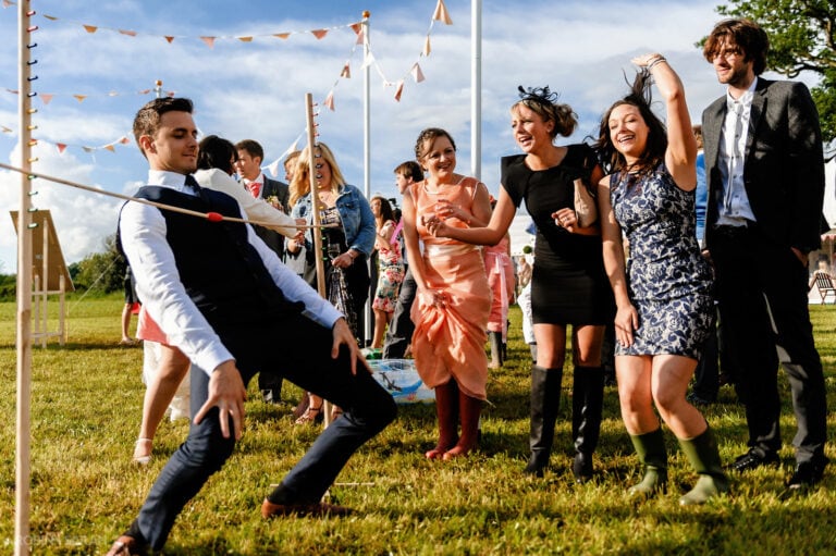 Wedding guests limbo dancing under pole at reception