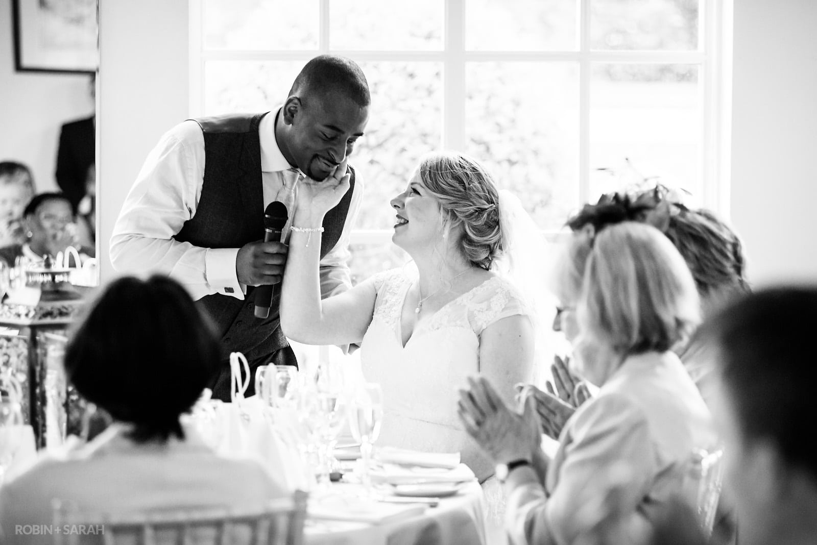 Bride smiling at groom as he gives wedding speech