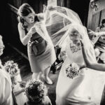 Bride has veil adjusted by bridesmaids as vicar talks to her before church wedding ceremony