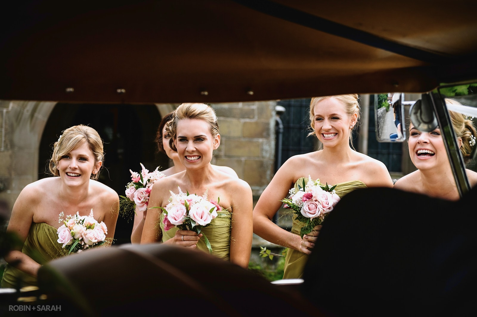 Bridesmaids react to seeing bride arrive at wedding in car