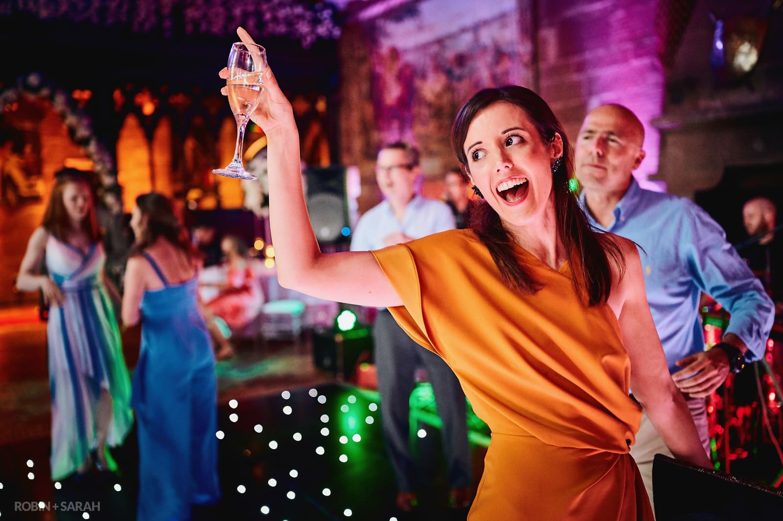 Wedding guest raises glass as she dances
