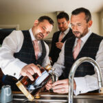 Groom pours brandy into hipflask before wedding