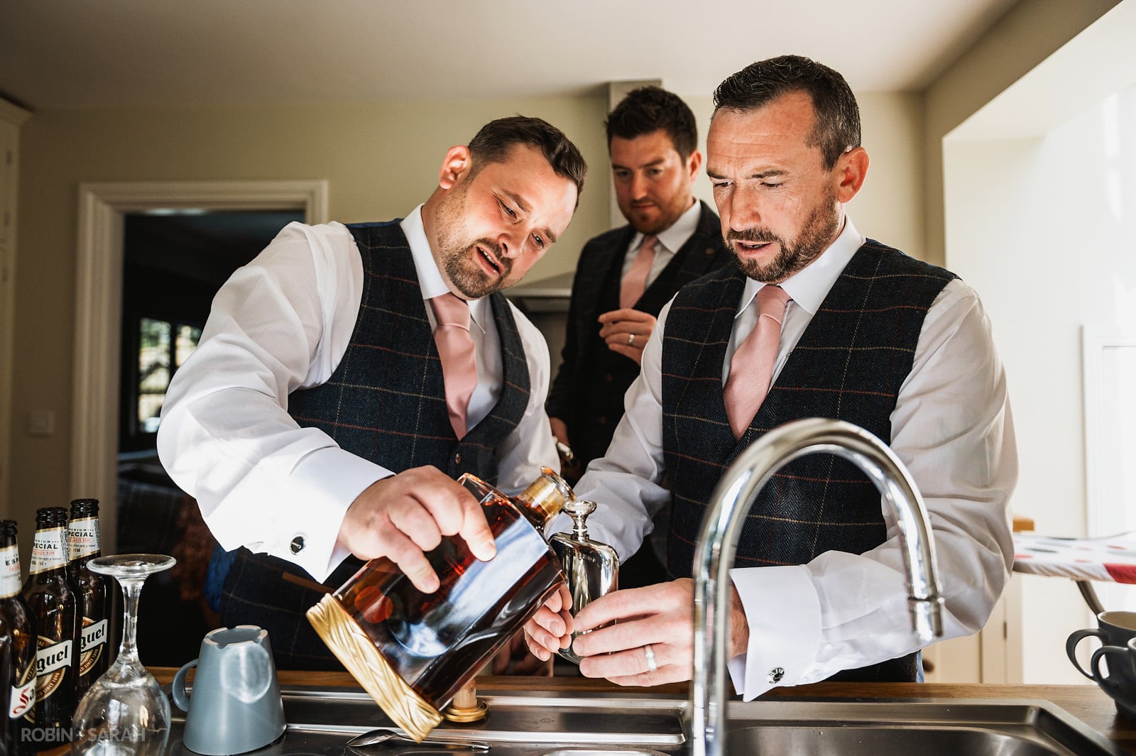 Groom pours brandy into hipflask before wedding