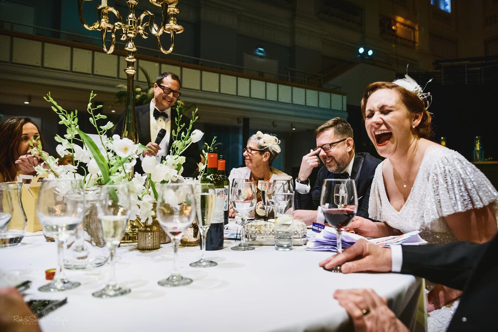 Bride laughing wildly during wedding speeches