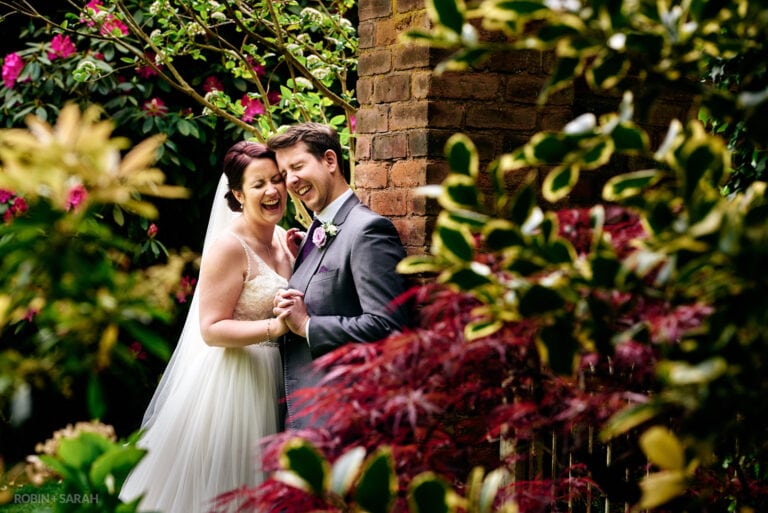 Bride and groom laughing together in gardens at Pendrell Hall