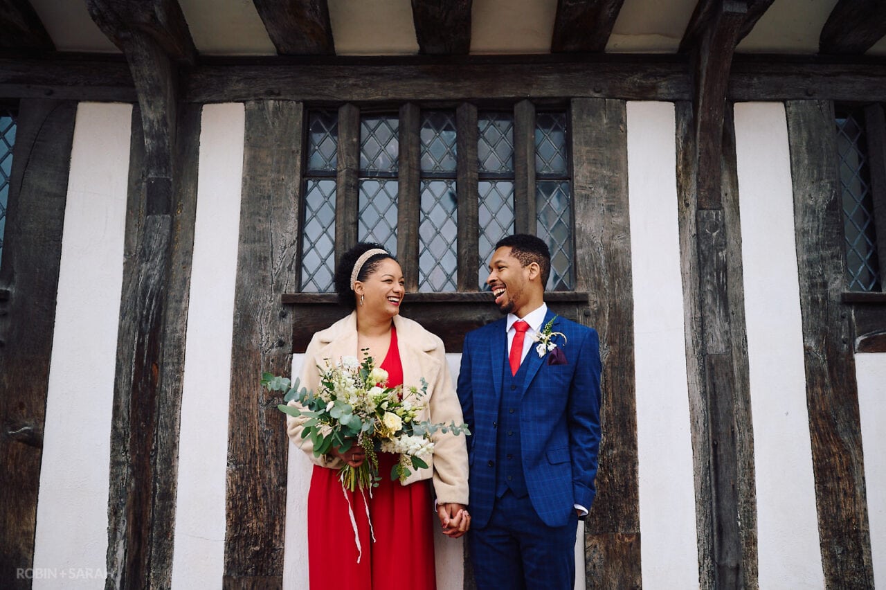 Bride and groom laughing together in front of old building in Stratford-upon-Avon