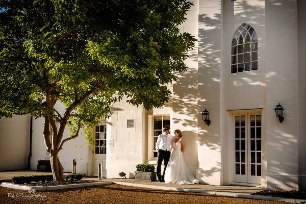 Bride and groom relax under tree at Warwick House in beautiful evening light