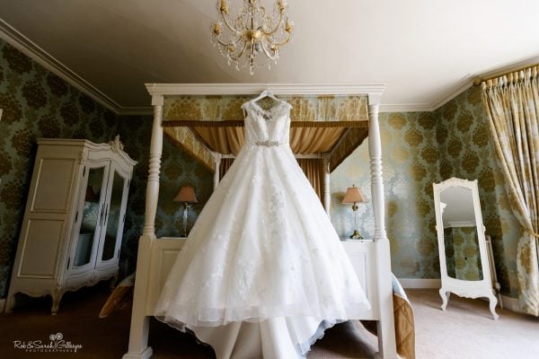 Wedding dress hanging on four-poster bed in beautiful room at Warwick House