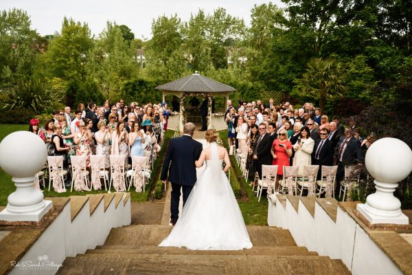 View from steps as bride and father walk up aisle at outdoor wedding ceremony