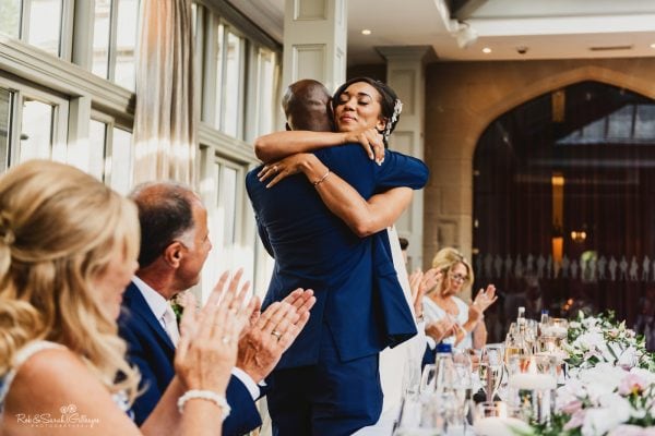 Bride hugs dad during wedding speeches as guests clap