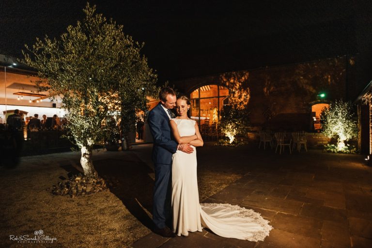 Bride and groom in courtyard at Swallows Nest Barn at night