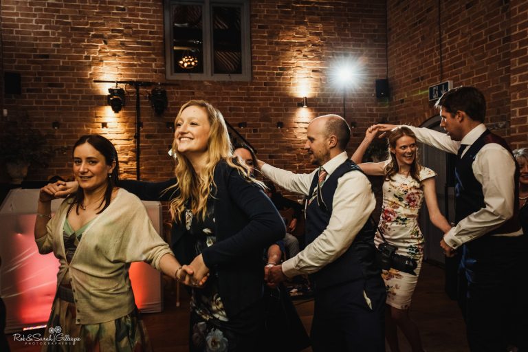 Wedding guests ceilidh dance at Swallows Nest Barn