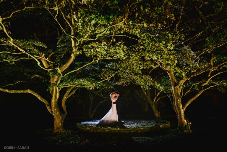 Bride and groom under beautiful trees lit up at night