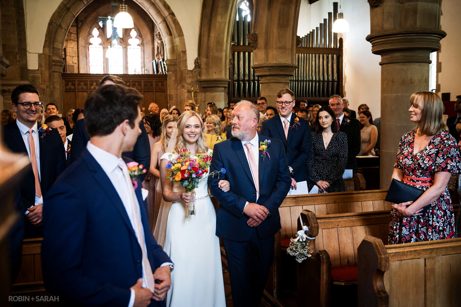 Bride and dad enter church as groom and guests watch