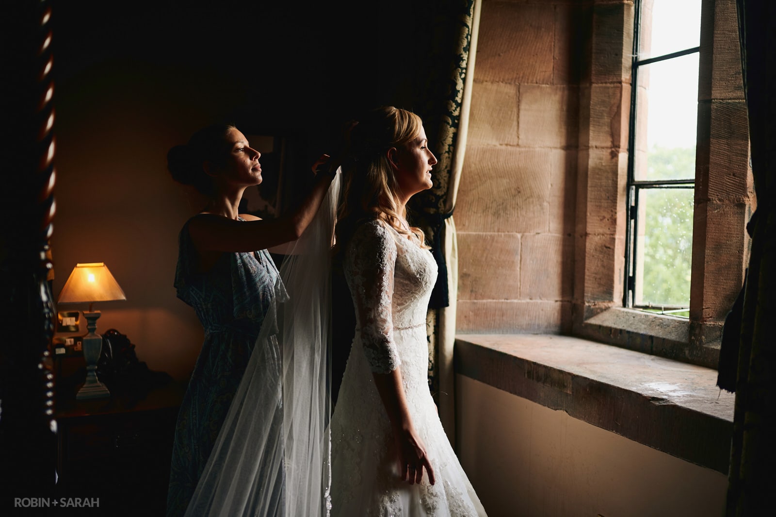 Bride in beautiful window light as she has veil fitted