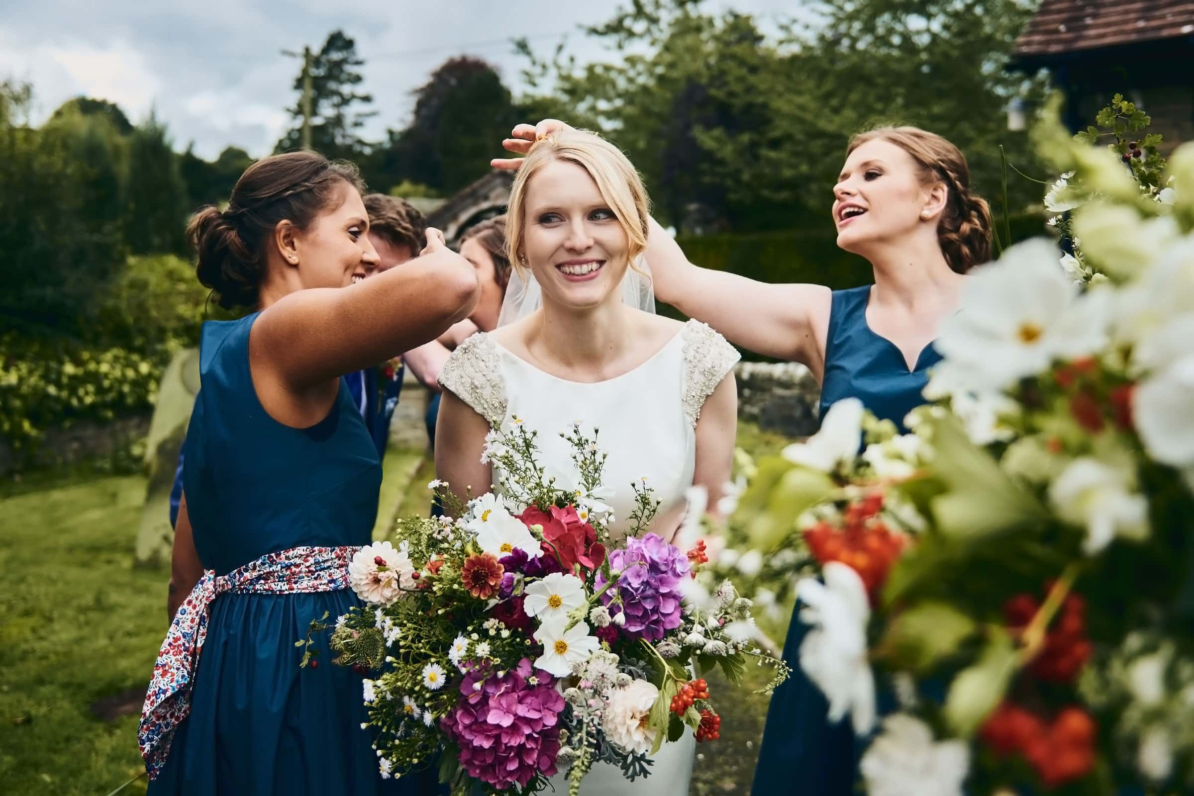 Bride laughing has bridesmaids pick confetti out of her hair