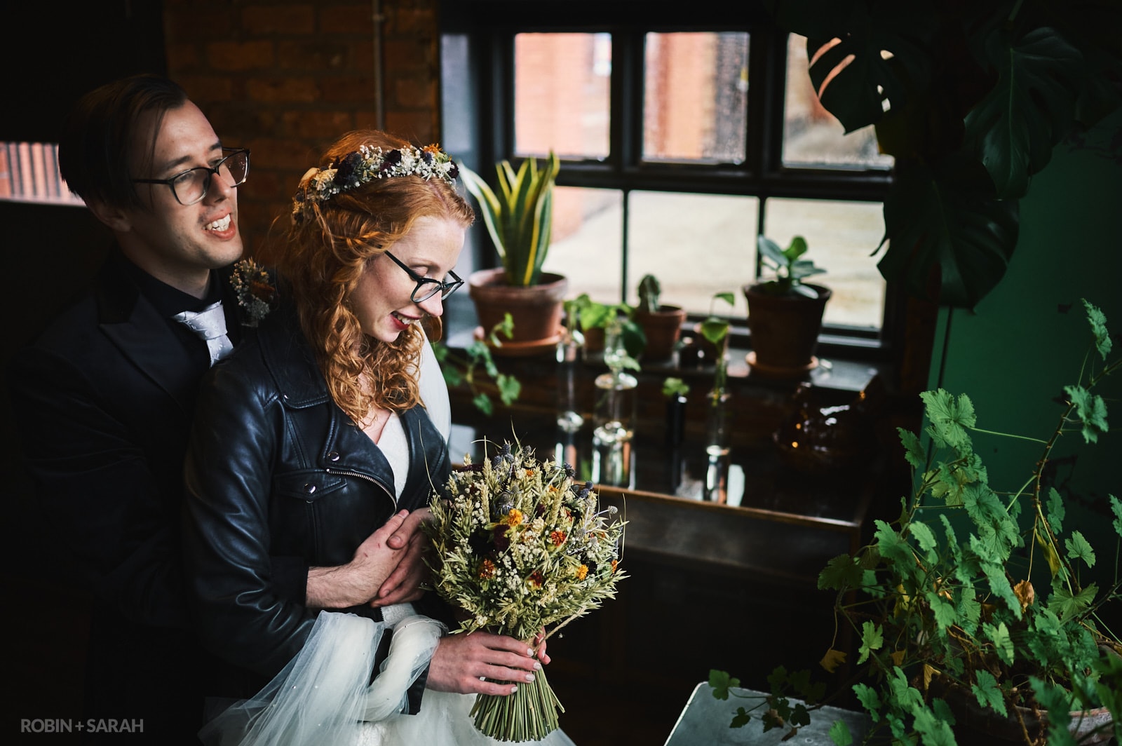 Alternative bride and groom in beautiful window light surrounded by potted plants