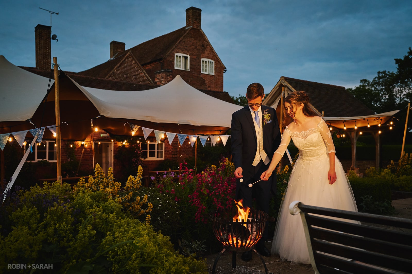 Bride and groom toast marshmallows on fire during evening wedding party