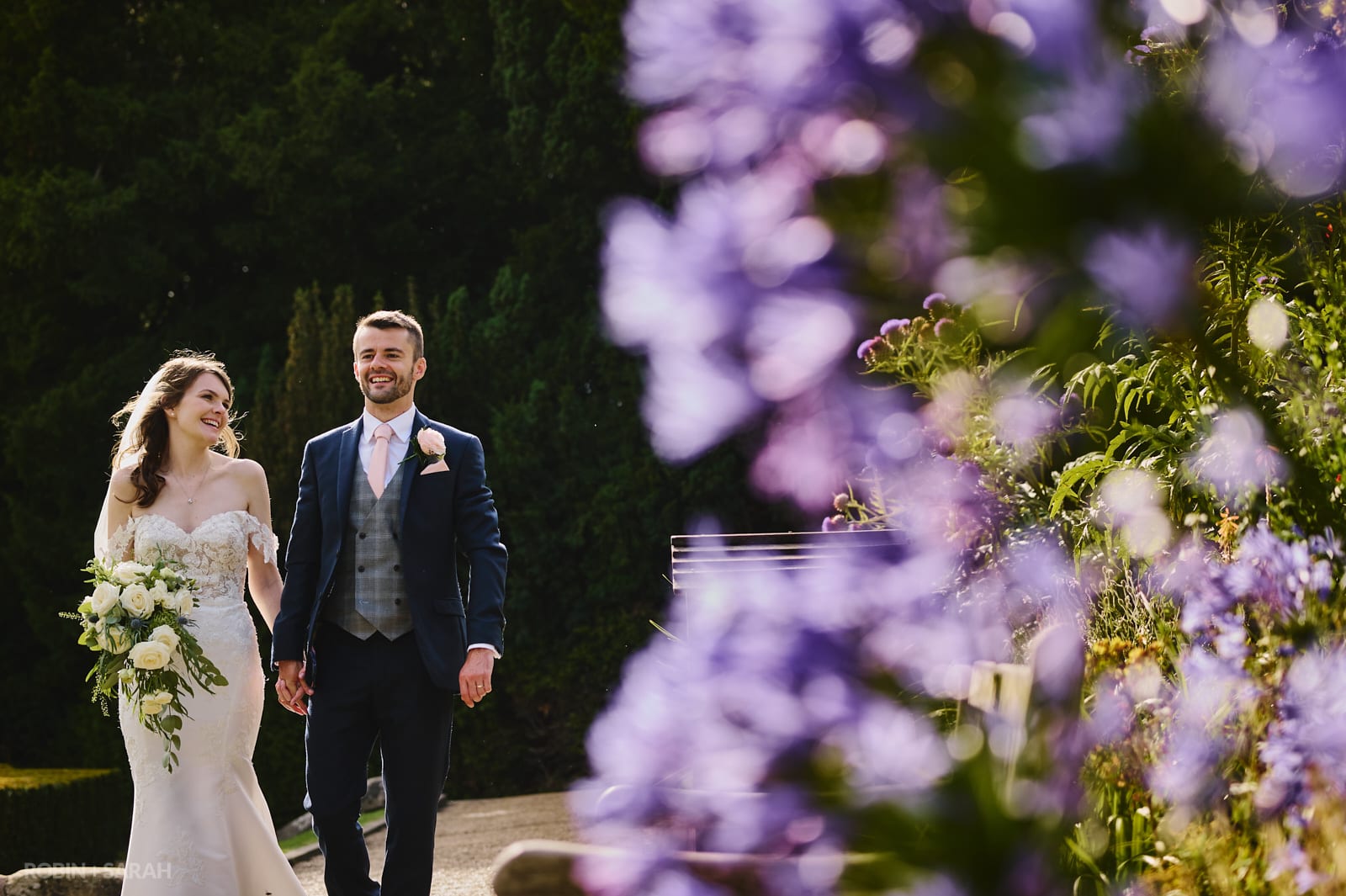 Bride and groom walk through beautiful gardens