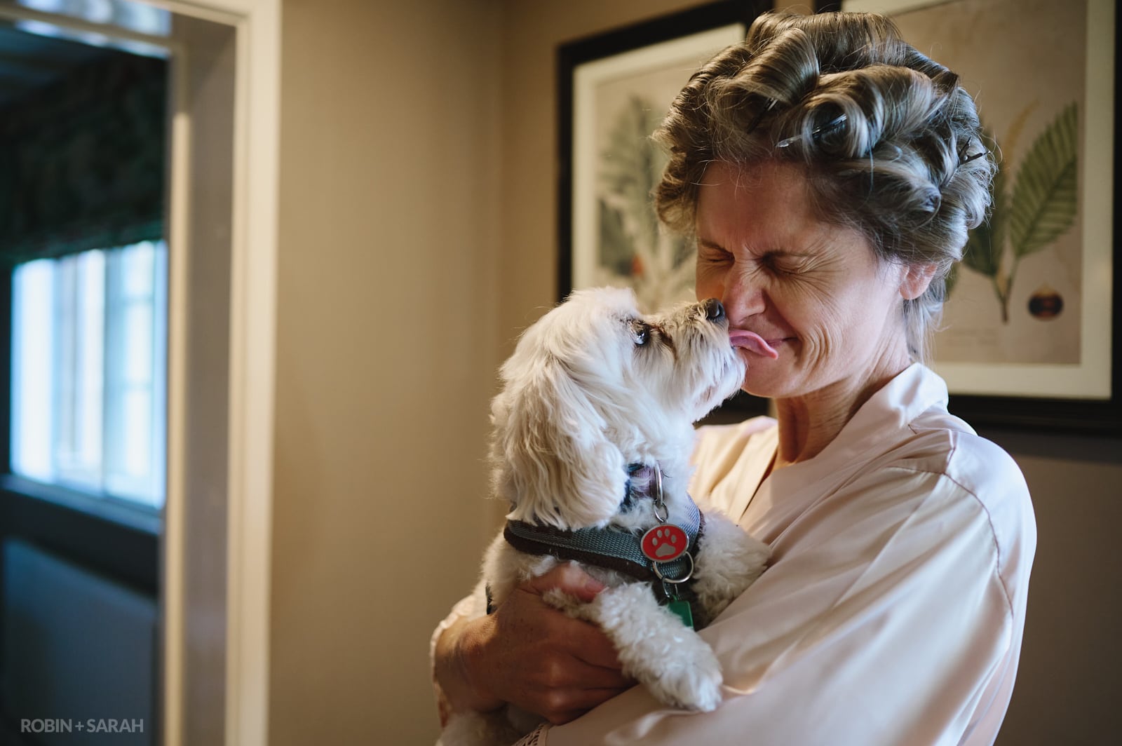 Bride has her face liked by small dog as she gets ready for wedding