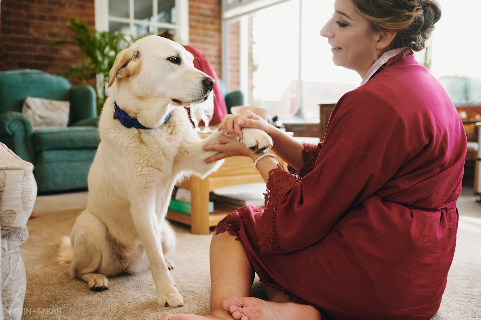 Bridesmaid plays with dog while getting ready for wedding