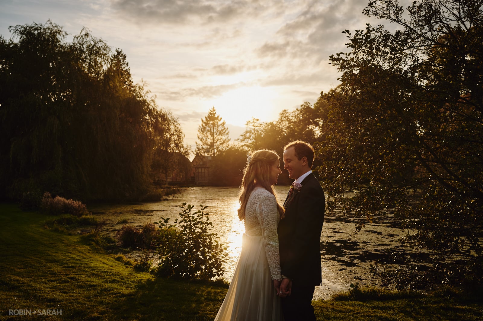 Bride and groom by the side of a lake with a beautiful sunset
