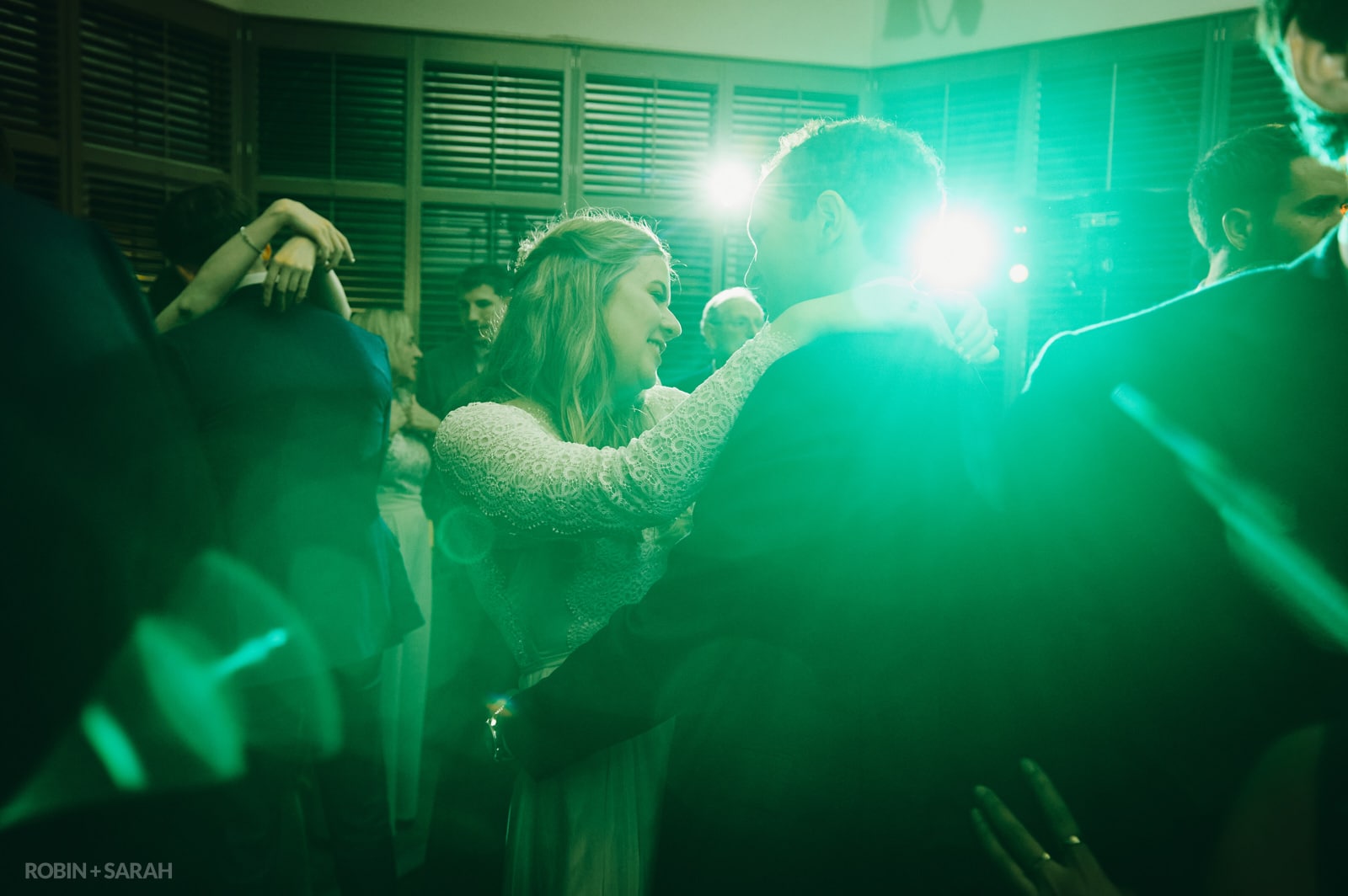 Bride and groom dancing at wedding surrounded by green lighting