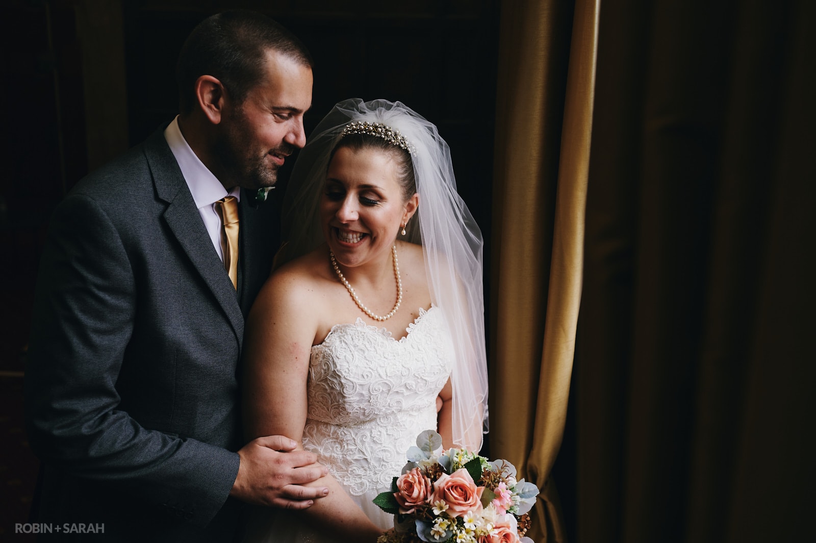 Bride and groom cuddle up in beautiful window light