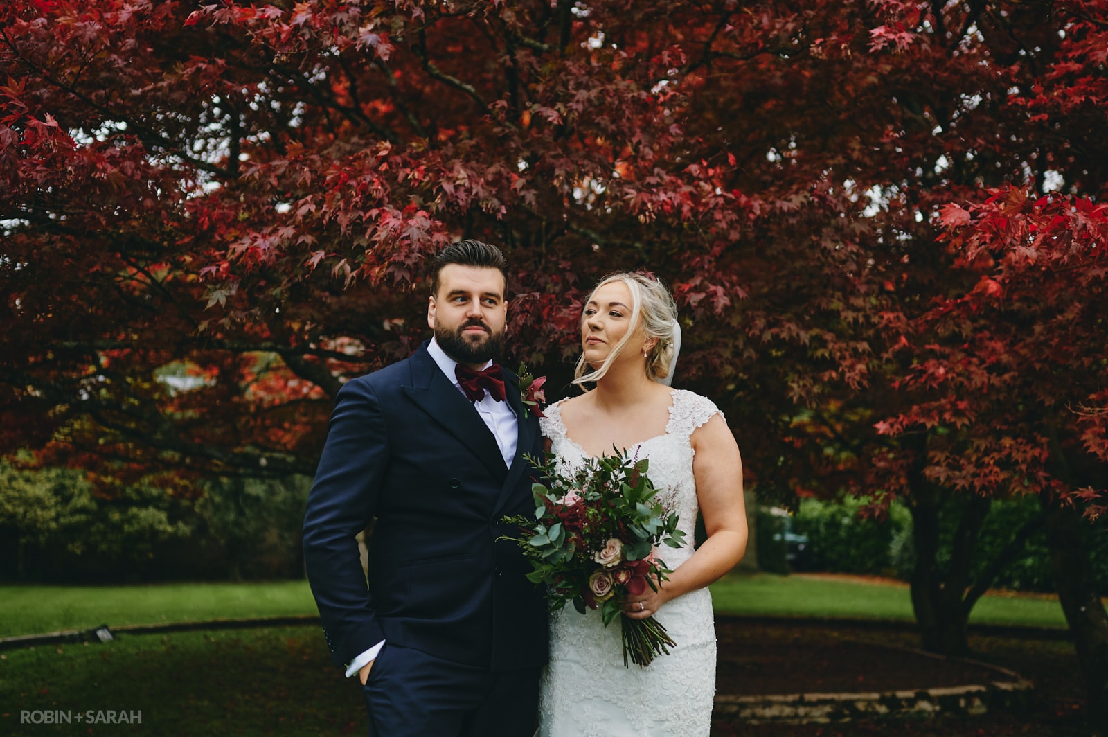 Bride and groom with playful expressions in front of beautiful red tree